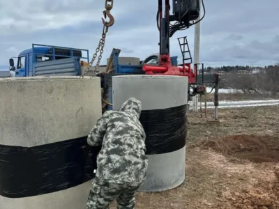 Опускание бетонных колец в шахту колодца